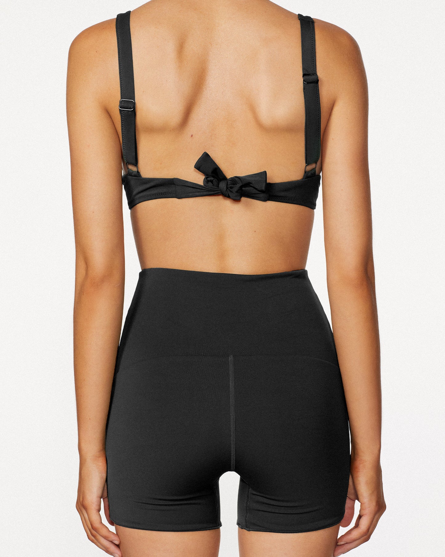 Model wearing the Contour Boy short in black, featuring its high rise waistband and compression fit.