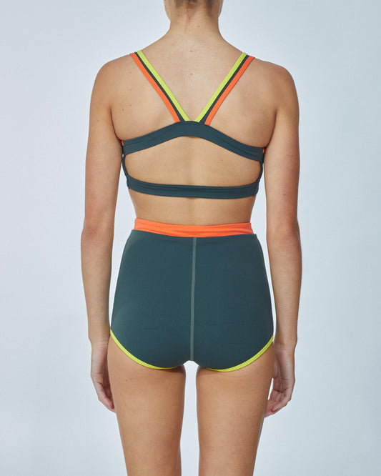Studio image of model wearing the Contour Duo Shortie in Admiral, showcasing its high waist line and full bottom coverage. 